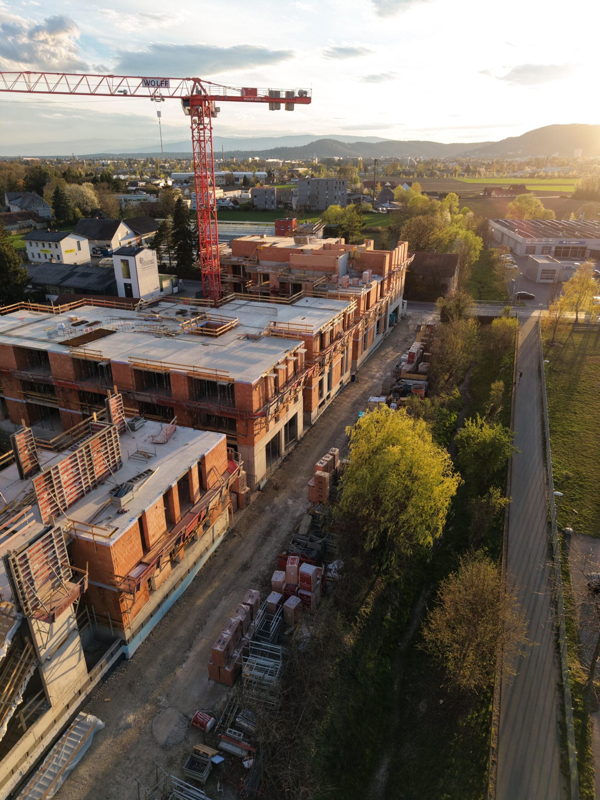 Wohnbau-Baustelle im Rohbau in Graz mit Kran, Drohnenfoto